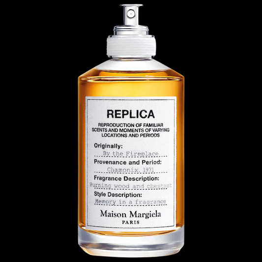 Imagen del perfume Maison Martin Margiela Replica By The Fireplace EDP, frasco rectangular transparente con etiqueta blanca característica de la línea Replica y líquido ámbar, fragancia unisex cálida y ahumada con castaña y vainilla, disponible en Costa Rica en decants y botella completa.